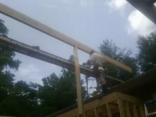 Carpenter setting a ridge beam over a new addition frame — Ice Dam Removal by Roofing Brothers in Plano