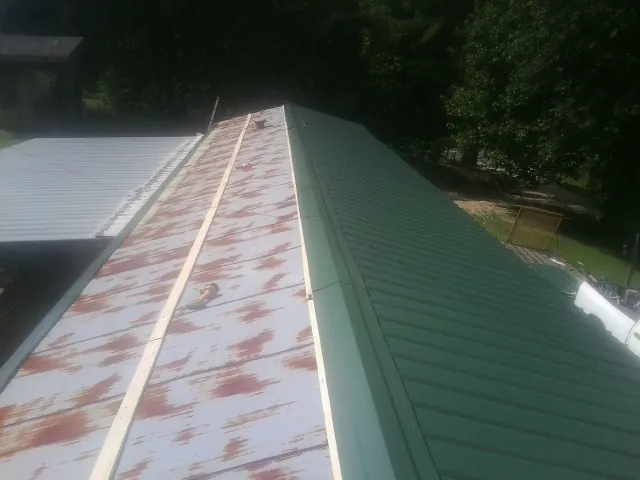 Old rusted panels beside newly installed green metal roofing — Wind Damage Roof Repair by Roofing Brothers in Plano