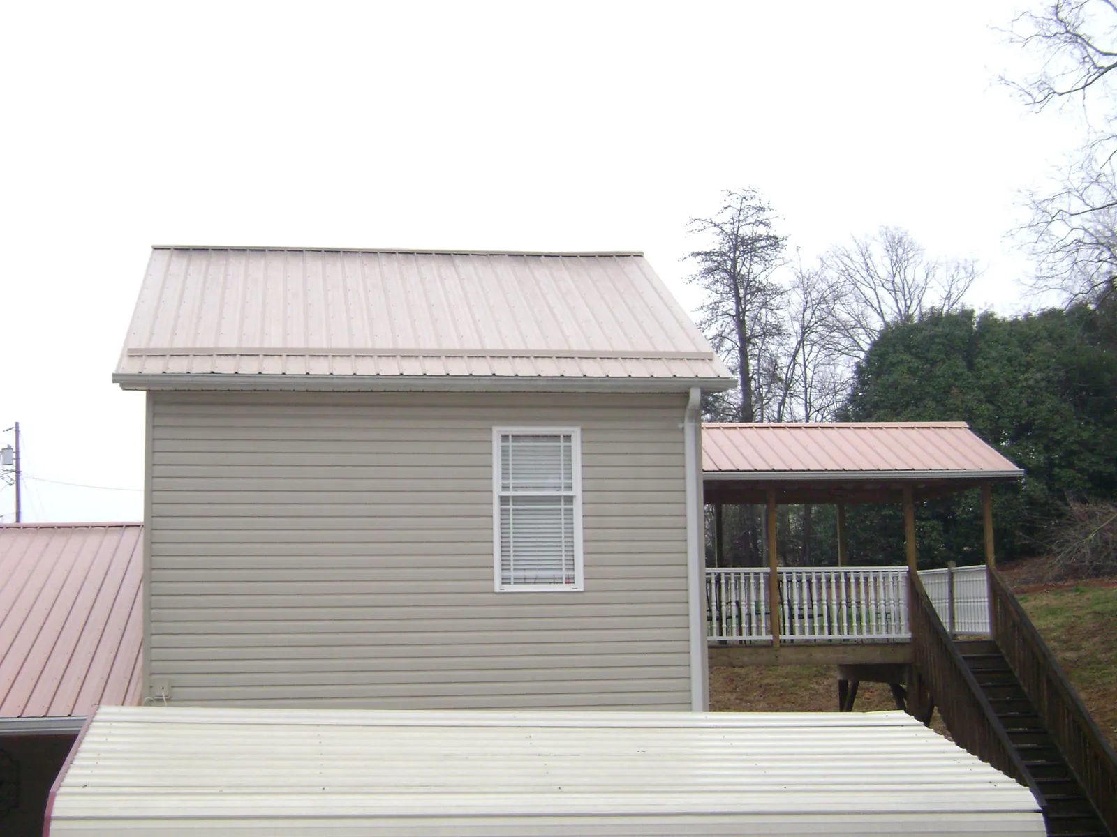 Tan metal roofs on a two story addition and attached porch, from a Roof Replacement job in Plano